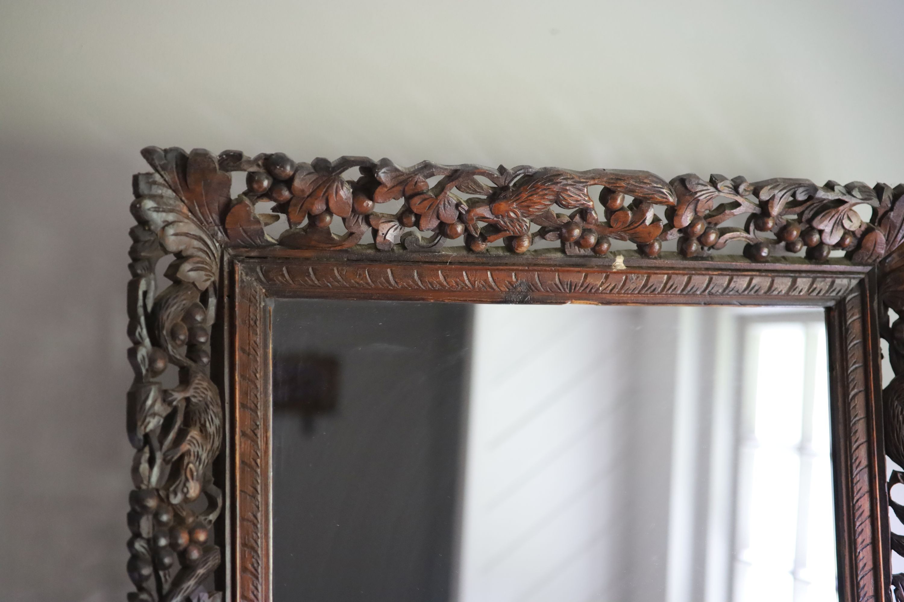 A Continental hardwood wall mirror, carved and pierced with squirrels and fruit, width 77cm height 63cm